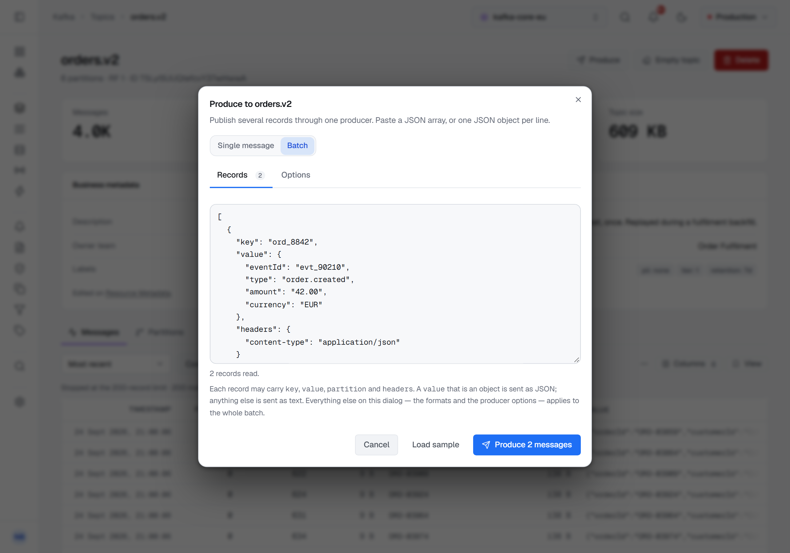 The Produce dialog for orders.v2 in Batch mode, on its Records tab with a count of 2 beside the Options tab: a JSON array whose first record carries a key ord_8842, an order.created value and a content-type header, the line 2 records read, a note on which fields a record may carry, and Cancel, Load sample and Produce 2 messages.